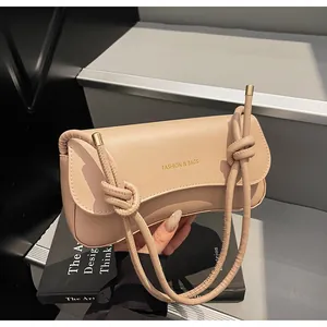 Detail of beige shoulder bag with gold text print and thick knotted rope strap detail
