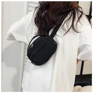 Close-up of black nylon crossbody bag featuring wide strap and white brand woven label