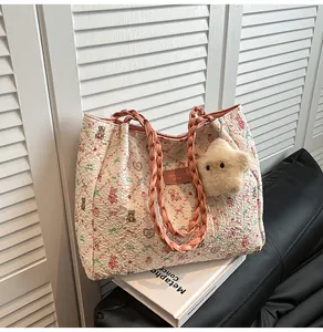 Detail of floral tote bag with woven pink handles and a plush star charm
