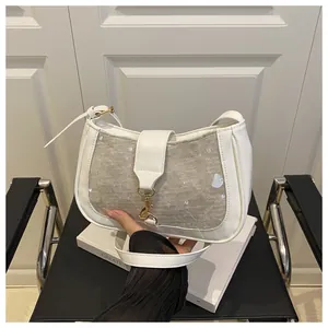 Close-up of white leather shoulder bag with sequined mesh panel and gold metal clasp