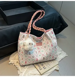 Close-up of white quilted tote bag with floral patterns and pink rope handles