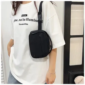 Detailed shot of a black nylon crossbody bag worn by a model showing the casual fit