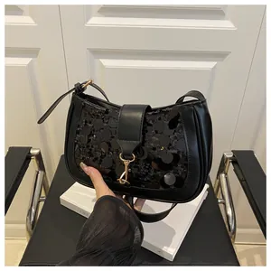 Detailed close-up of a black sequin baguette bag featuring a gold clasp and smooth strap