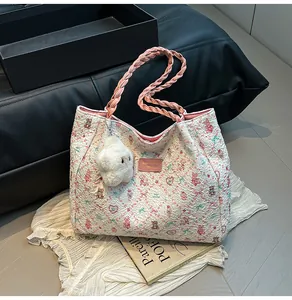 Detail of floral tote bag with white bubble texture, pink woven handles and cute plush charm
