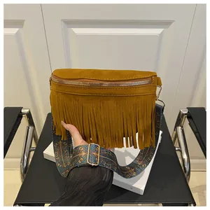Close-up of mustard yellow suede crossbody bag with long tassels and ethnic pattern strap