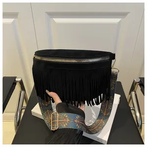 Detail of black suede waist bag featuring long fringes and ethnic patterned shoulder strap