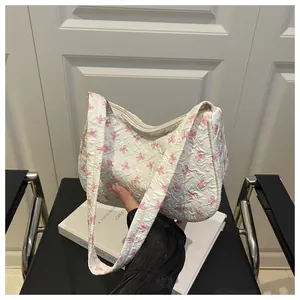 Close-up of floral quilted shoulder bag featuring pink bow patterns and zipper detail