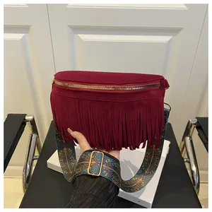 Detail of burgundy suede fanny pack with tassels and vintage pattern wide strap
