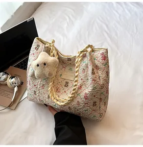 Detail of cream tote bag with bear floral print, braided handles and plush star charm
