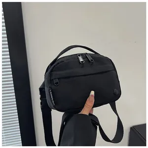 Detailed close-up of a black nylon crossbody bag with dual zippers and woven brand label