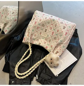 Detail of floral tote bag featuring white woven rope handles and a star plush charm