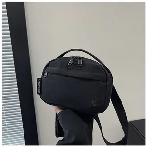 Detail of black nylon crossbody bag featuring dual metal zippers and branded woven label