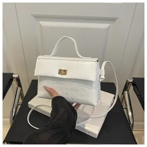 Detailed view of white houndstooth embossed Kelly bag with gold metal rotary lock closure