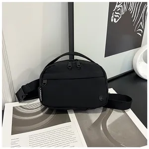 Detail of black nylon crossbody bag featuring double zippers and a side brand tag