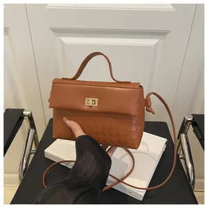 Close-up of caramel leather handbag featuring golden lock and houndstooth texture detail