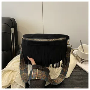 Close-up of black suede crossbody bag with long fringes and ethnic patterned strap