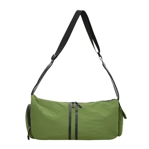 Detalle del bolso cilíndrico de nailon verde con bolsillo lateral y correa ajustable