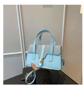 Detail of light blue crossbody bag with woven texture flap and metallic twist lock closure