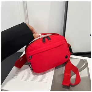Detail of red nylon crossbody bag showing the durable fabric texture and dual-zipper closure