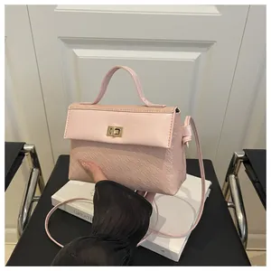Detail of pink crossbody bag with houndstooth texture and golden metal rotary lock
