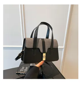 Detail of hand-held bag featuring two-tone grey fabric and black leather with gold lock