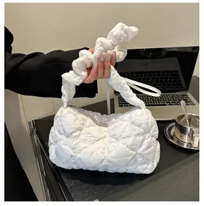 Detailed shot of white quilted bubble bag with puffy texture and ruffled strap in office setting