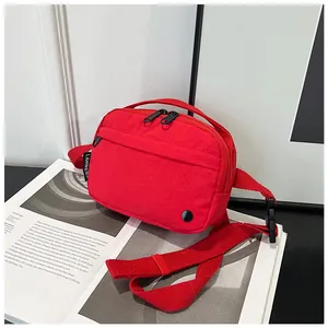 Detail of red nylon crossbody bag with zipper pockets and durable shoulder strap buckle