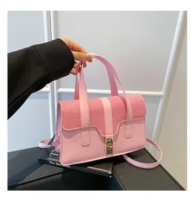 Close-up of pink woven crossbody bag featuring a golden metallic twist lock and handle