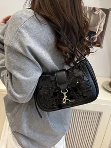 Chic black sequin underarm bag with gold clasp shown on model for elegant shoulder wear