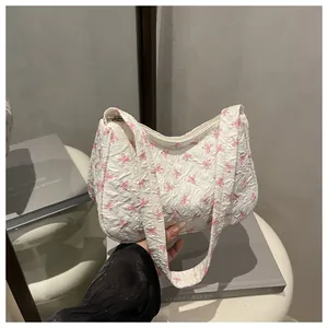 Detail of floral shoulder bag with pink bow prints and textured pleated fabric surface
