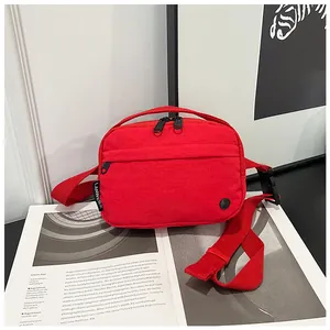 Detail of red nylon crossbody bag with dual zippers and adjustable shoulder strap