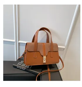 Detail of brown leather handbag with woven flap, golden twist lock and adjustable shoulder strap