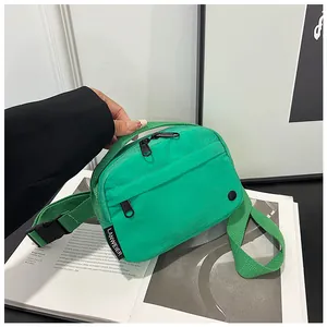Close-up of bright green nylon crossbody bag showing the zipper and brand label details