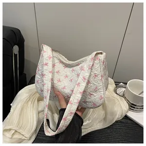 Macro detail of white shoulder bag featuring pink bow prints and pleated texture fabric