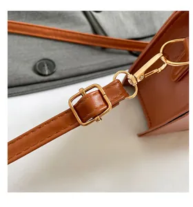 Detailed close-up of brown faux leather strap with gold buckle and stitching detail