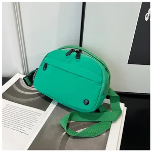 Detail view of the bright green nylon crossbody bag with dual zippers and woven strap