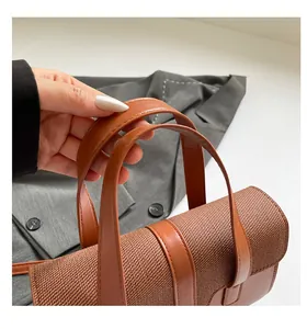 Detail of brown woven fabric and smooth leather handbag with sturdy double handles