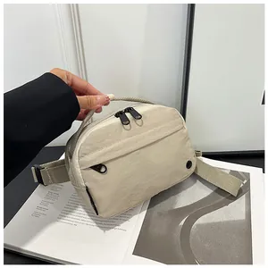 Detailed close-up of beige nylon crossbody bag with water-resistant fabric and dual zippers