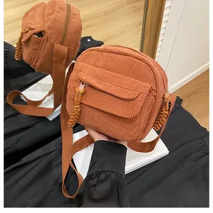 Detailed mirror shot of caramel corduroy square crossbody bag with woven zipper puller