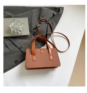 Detailed view of brown woven handbag with long shoulder strap on gray blazer background