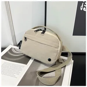 Detail view of the beige nylon crossbody bag texture with black brand woven label