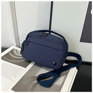 Detail of navy nylon crossbody bag with dual zippers and woven brand label on magazine