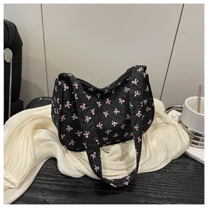 Detail view of the black textured fabric and pink bow prints on this stylish shoulder bag