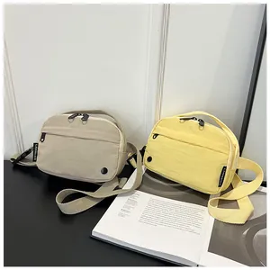 Close-up of beige and yellow nylon crossbody bags with dual zippers and adjustable straps