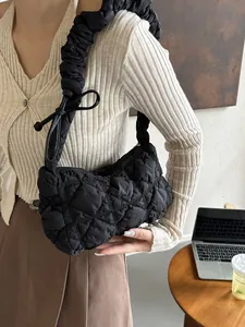Black quilted puffer cloud bag with ruched handle and bow tie detail on a wooden table