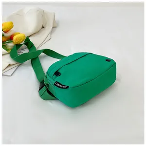 Detail view of the green nylon shoulder bag featuring a branded fabric label and black strap