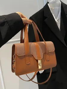 Brown leather and woven crossbody bag with gold buckle held by a model in a black suit