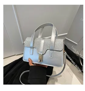 Detail of silver textured handbag featuring a sparkling rhinestone flap and golden twist lock