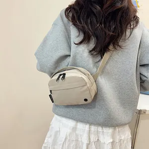 Minimalist beige nylon crossbody bag with dual zippers and adjustable wide strap