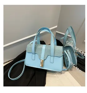 Close-up of light blue handbag with glitter panel, metallic twist lock and mirror reflection
